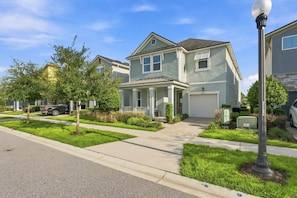 A two-story residential house with a front porch, a garage, and a well-maintained lawn.