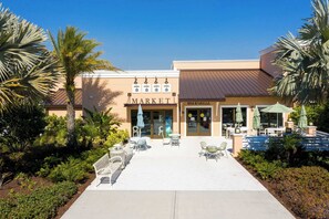 Un bâtiment avec une enseigne indiquant « MARCHÉ », des tables à l’extérieur et des palmiers.
