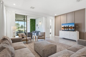 A modern living room with a sofa set, a television, and a cityscape view. - Stunning Retreat, Private Pool, Perfect Location (Kissimmee)