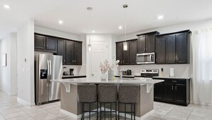Una cocina moderna con armarios de madera oscura, electrodomésticos de acero inoxidable y una isla central con taburetes de bar.