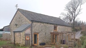 A stone building with a grassy yard and a small pond.