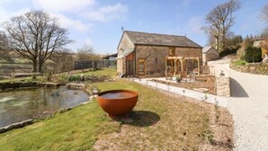 A stone building with a pond and a large red pot in the foreground.