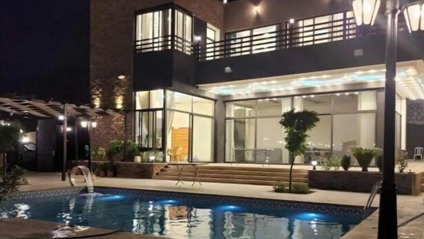 A modern two-story house with a swimming pool, outdoor lighting, and a well-maintained garden.