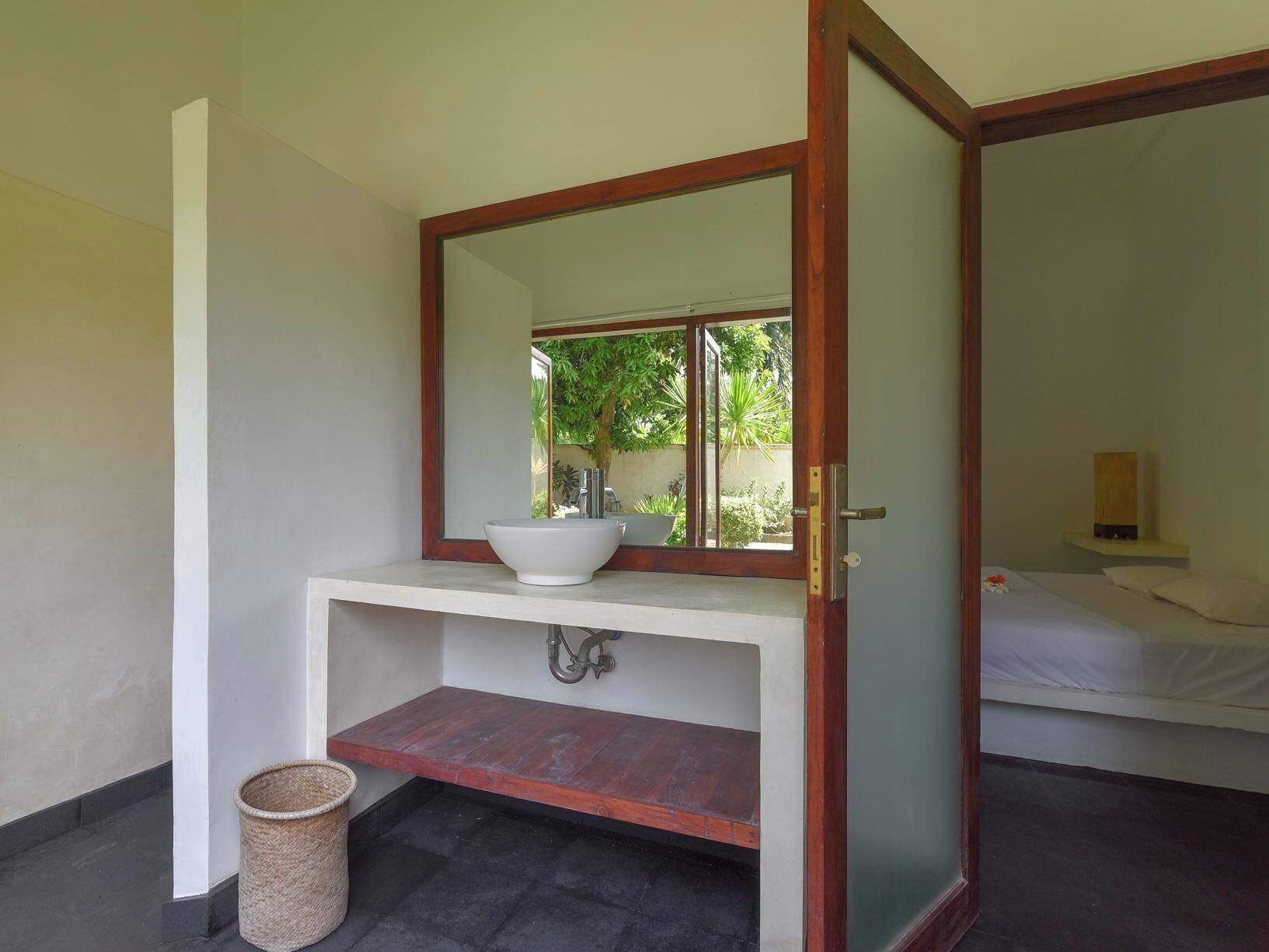 A bathroom with a white sink, a mirror, and a wooden bench.