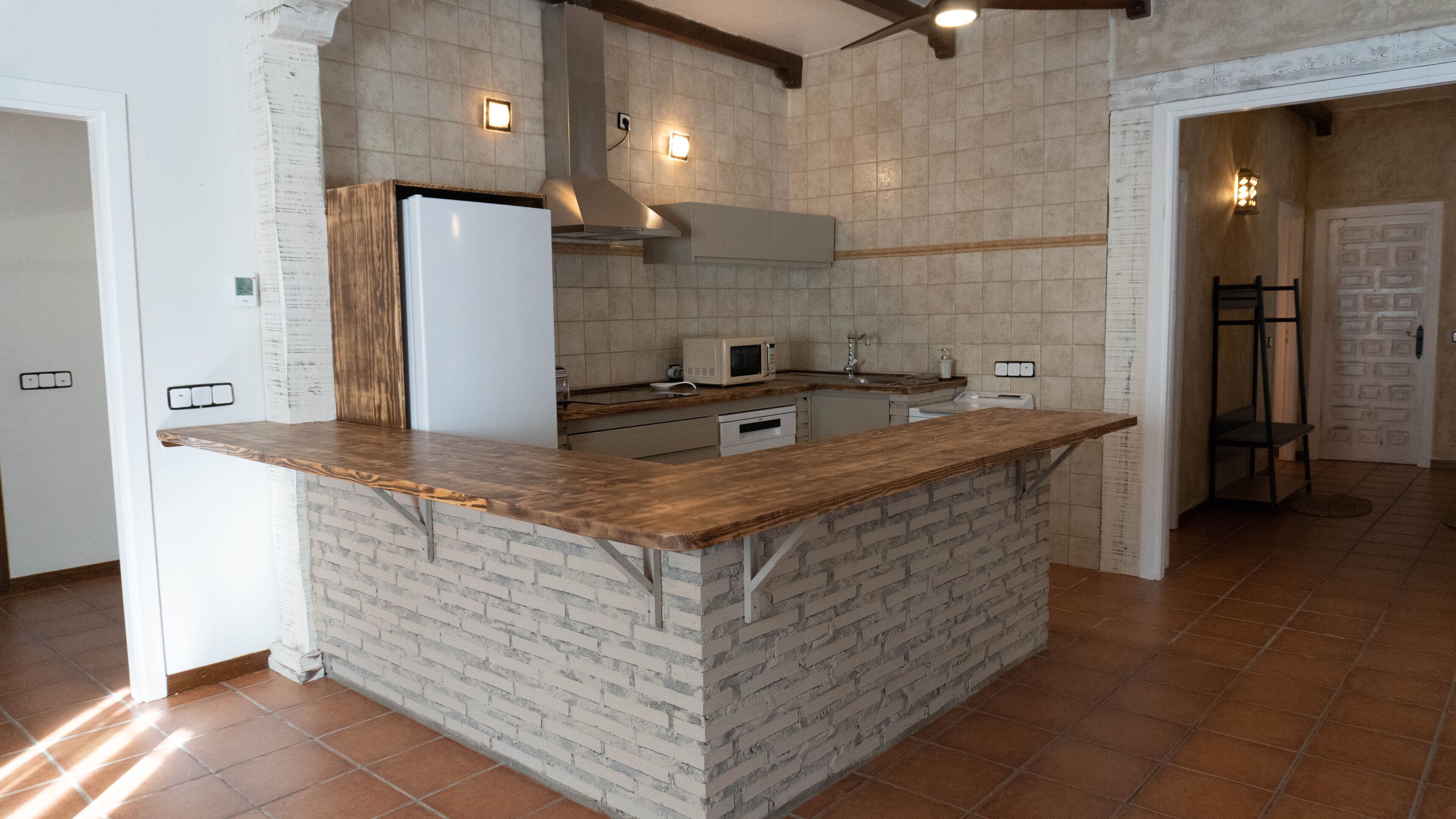 A kitchen with a brick island counter, a refrigerator, a microwave, and a stove.