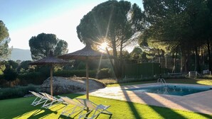 Et poolområde med en pergola, liggestole og en velplejet græsplæne.