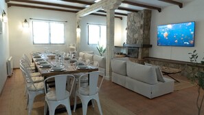 Un comedor con una larga mesa de madera dispuesta para seis personas, rodeada de sillas blancas.