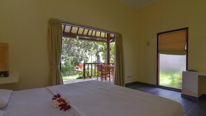 Una camera d'albergo con un letto, una scrivania e vista su un giardino.