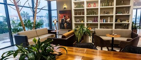 A modern interior with a wooden table, sofas, and a bookshelf filled with various items.