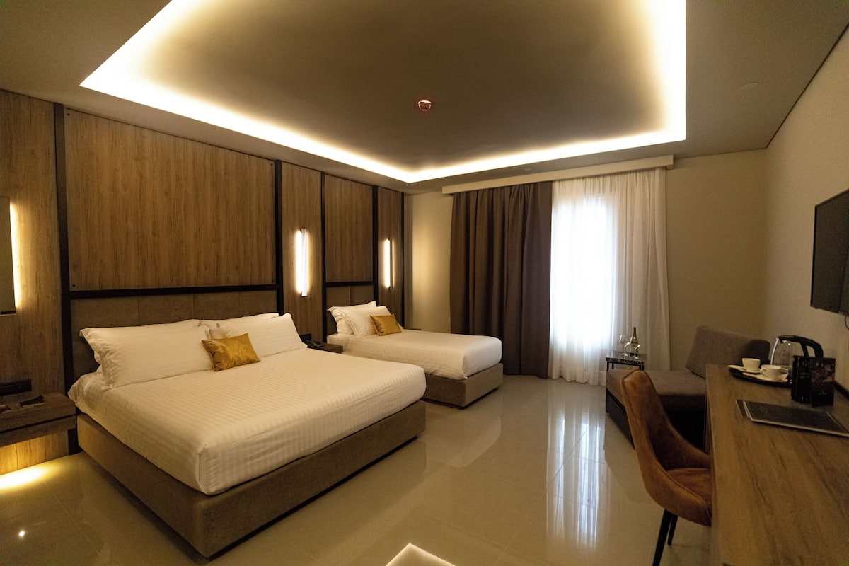 Une chambre d’hôtel moderne équipée d’un grand lit, d’un lit plus petit, d’un bureau et d’une chaise.