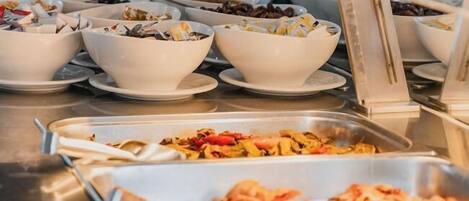 A buffet with various dishes including salads, fruits, and seafood.