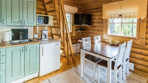 L’intérieur d’une cabane en bois comprend une cuisine, un coin repas et un téléviseur fixé au mur.