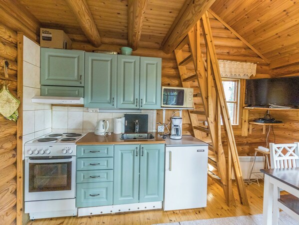 Cocina compacta con estufa, microondas y cafetera.
