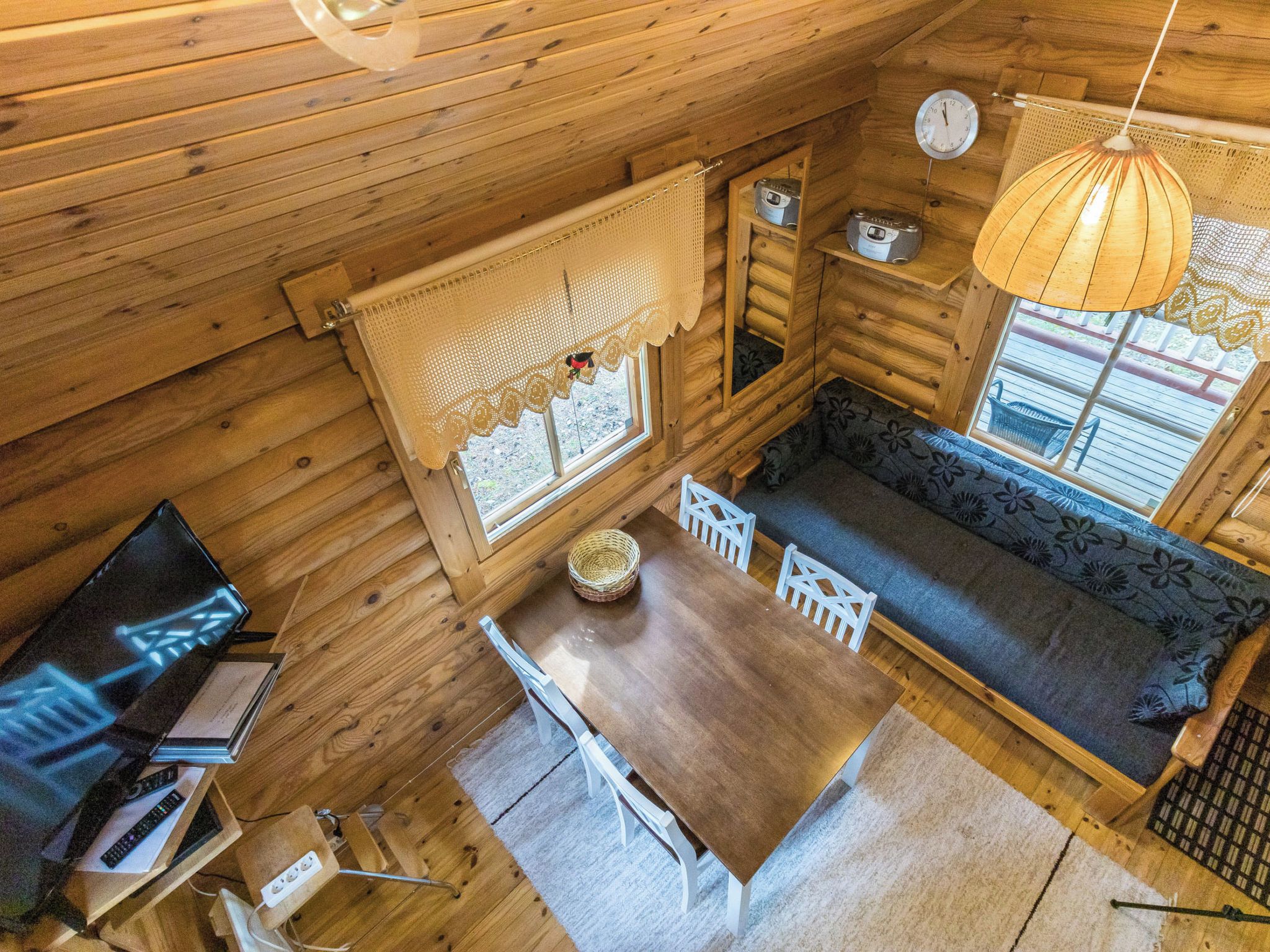 Interior acogedor de una cabaña con una mesa de comedor de madera, un sofá y una ventana con vistas.
