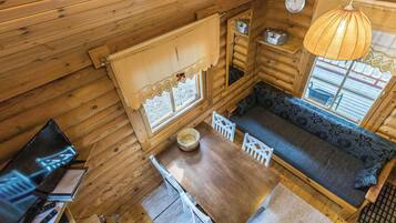 Interior acogedor de una cabaña con una mesa de comedor de madera, un sofá y una ventana con vistas.