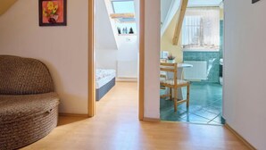 Une pièce chaleureuse avec un canapé incurvé, un lit et une lucarne donnant sur un balcon équipé d’une table et de chaises.