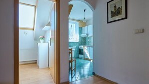 Une cuisine moderne donnant sur l’extérieur, un coin repas avec une table et des chaises, et un couloir menant à une autre pièce.