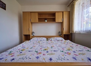 Un dormitorio con cama, armario de madera y ventana con cortinas.