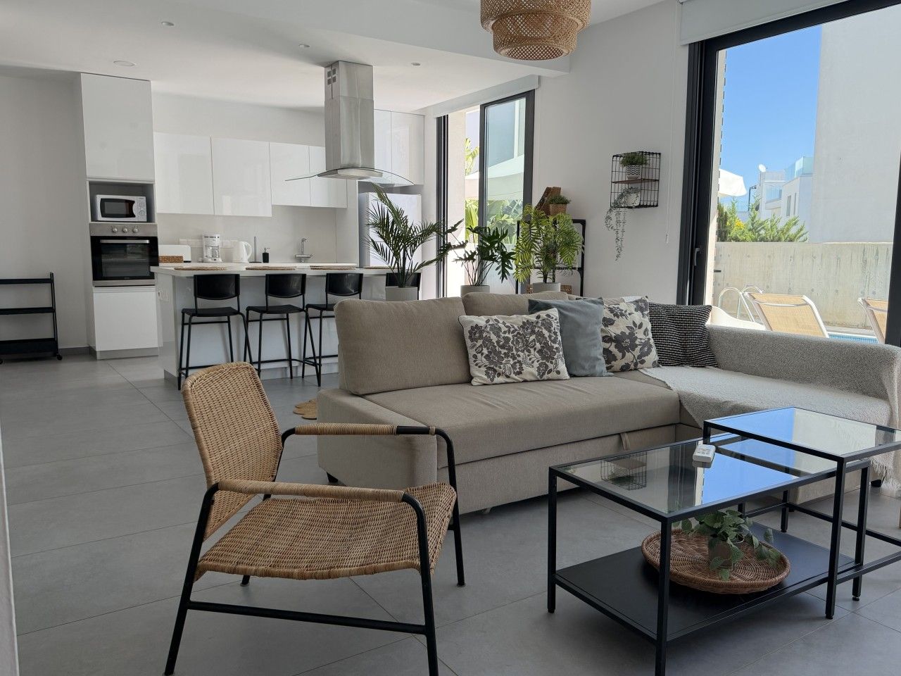 Un espace de vie moderne comprenant un canapé, une table basse en verre et un fauteuil en osier.