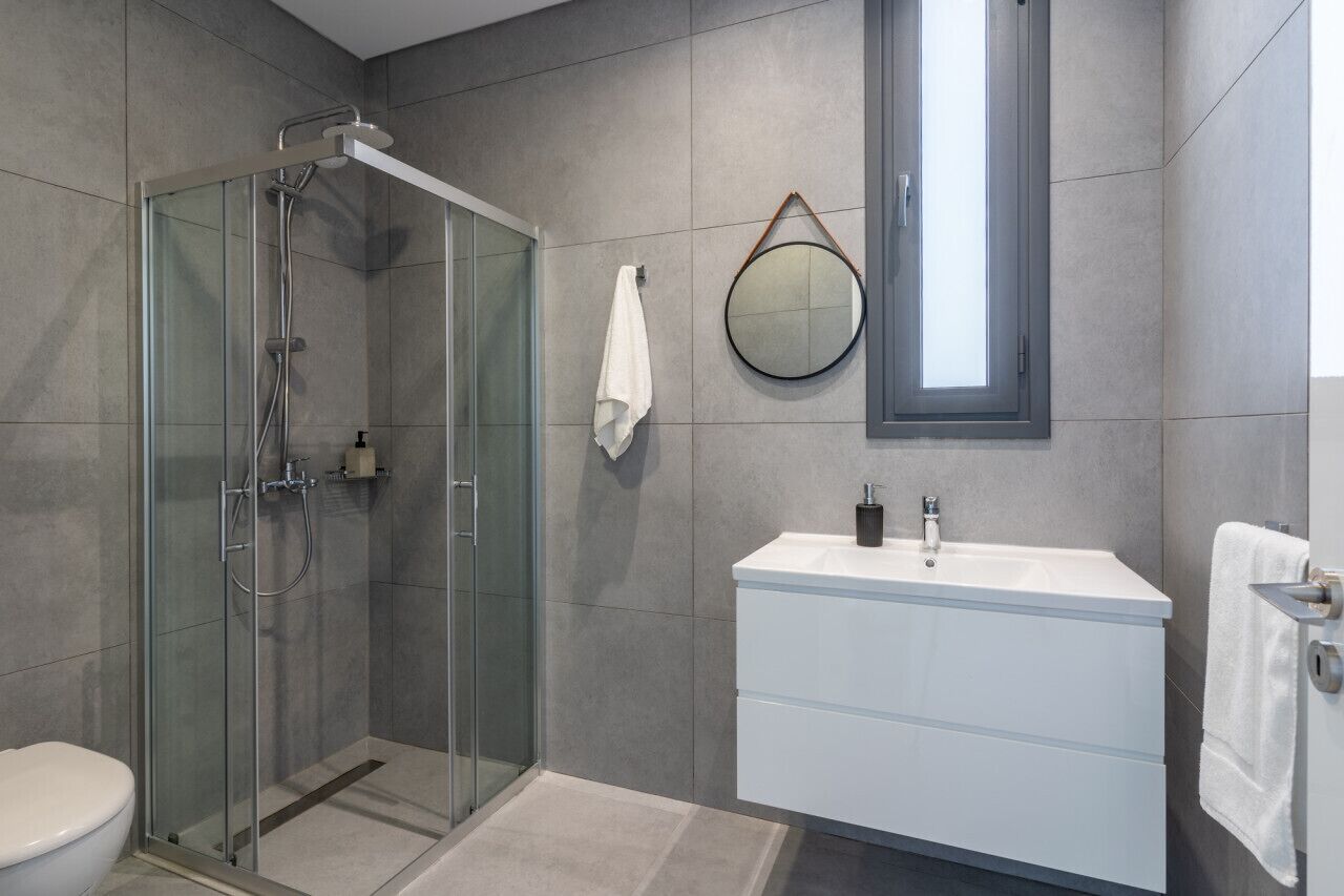 A modern bathroom with a glass-enclosed shower, a white vanity with a mirror, and a toilet.