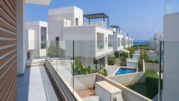 Ein moderner Wohnkomplex mit Pool, Außenbereich zum Sitzen und freiem Blick auf das Meer.