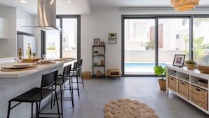 Eine moderne Küche mit Kochinsel, Barhocker und einem großen Fenster mit Blick auf einen Pool.
