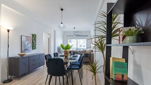 A modern dining area with a wooden floor, black chairs, a glass table, and a potted plant. - Citrus 3-Bedroom Apartment in Larnaca (Larnaca)