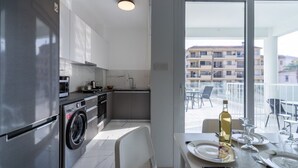 Een moderne keuken met een roestvrijstalen koelkast, een wasmachine en een eethoek met een tafel gedekt voor twee personen.