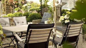 An outdoor patio with wicker furniture, a stone statue, and various potted plants. - Höhen Hotel Viersen (Viersen)