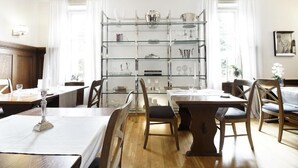 A dining area with a central glass display case, wooden tables, and chairs. - Höhen Hotel Viersen (Viersen)