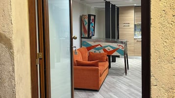 Un espace intérieur doté d’une porte à cadre en bois, d’un canapé et d’une table ornée d’un motif géométrique aux couleurs vives.