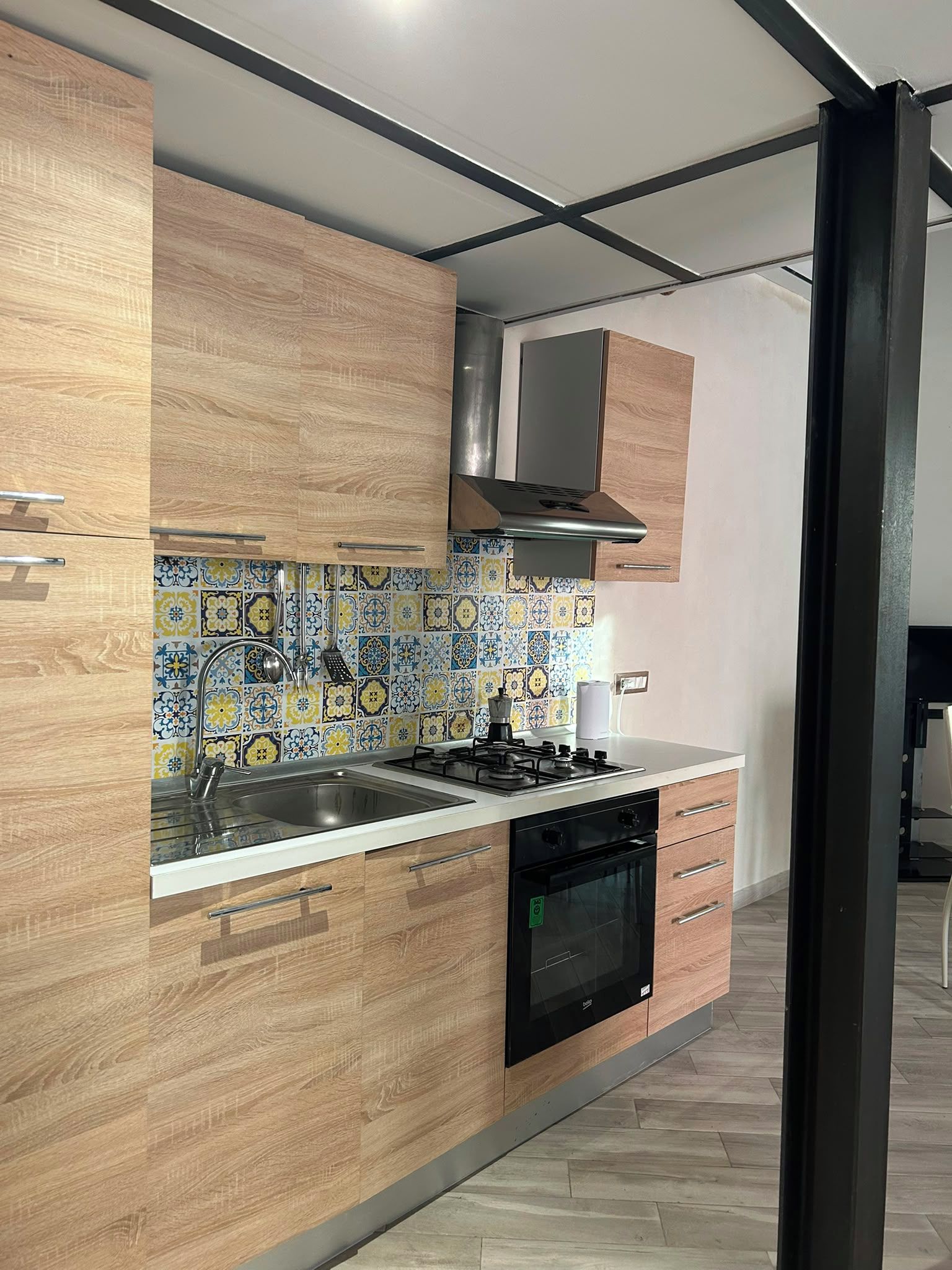 A modern kitchen with wooden cabinets, a tiled backsplash, and a built-in oven.