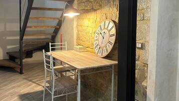 Une pièce de style loft avec un bureau en bois, une chaise, une horloge, un escalier et un mur en pierre.
