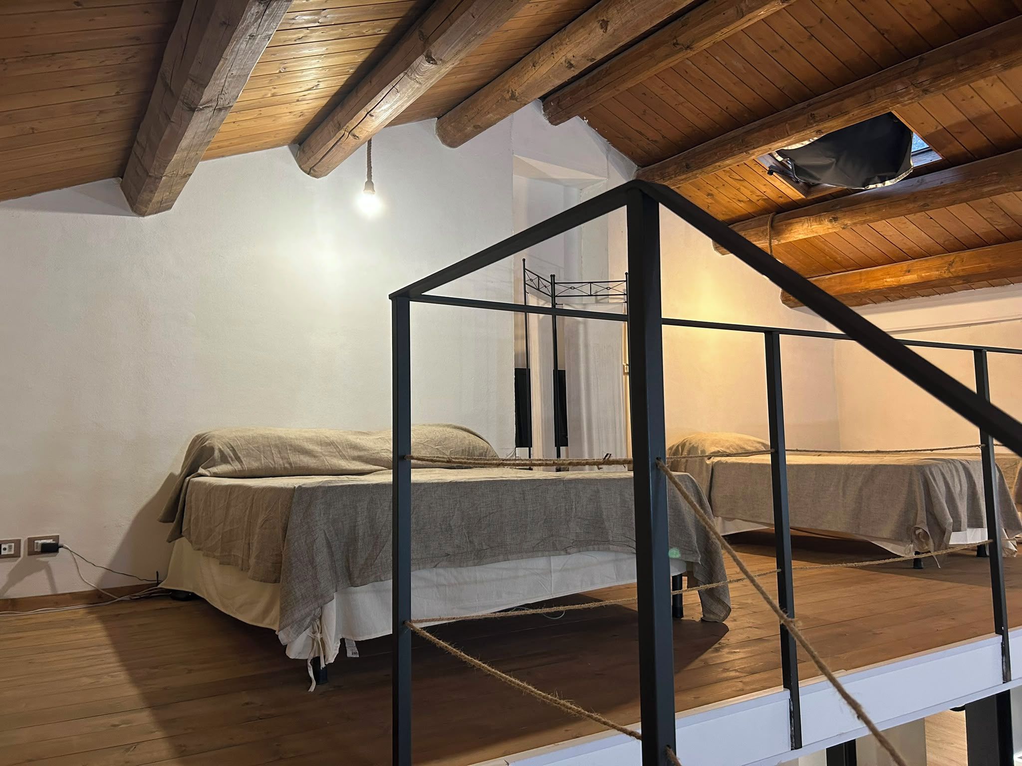 Una camera da letto con due letti, travi in legno a soffitto e una finestra.