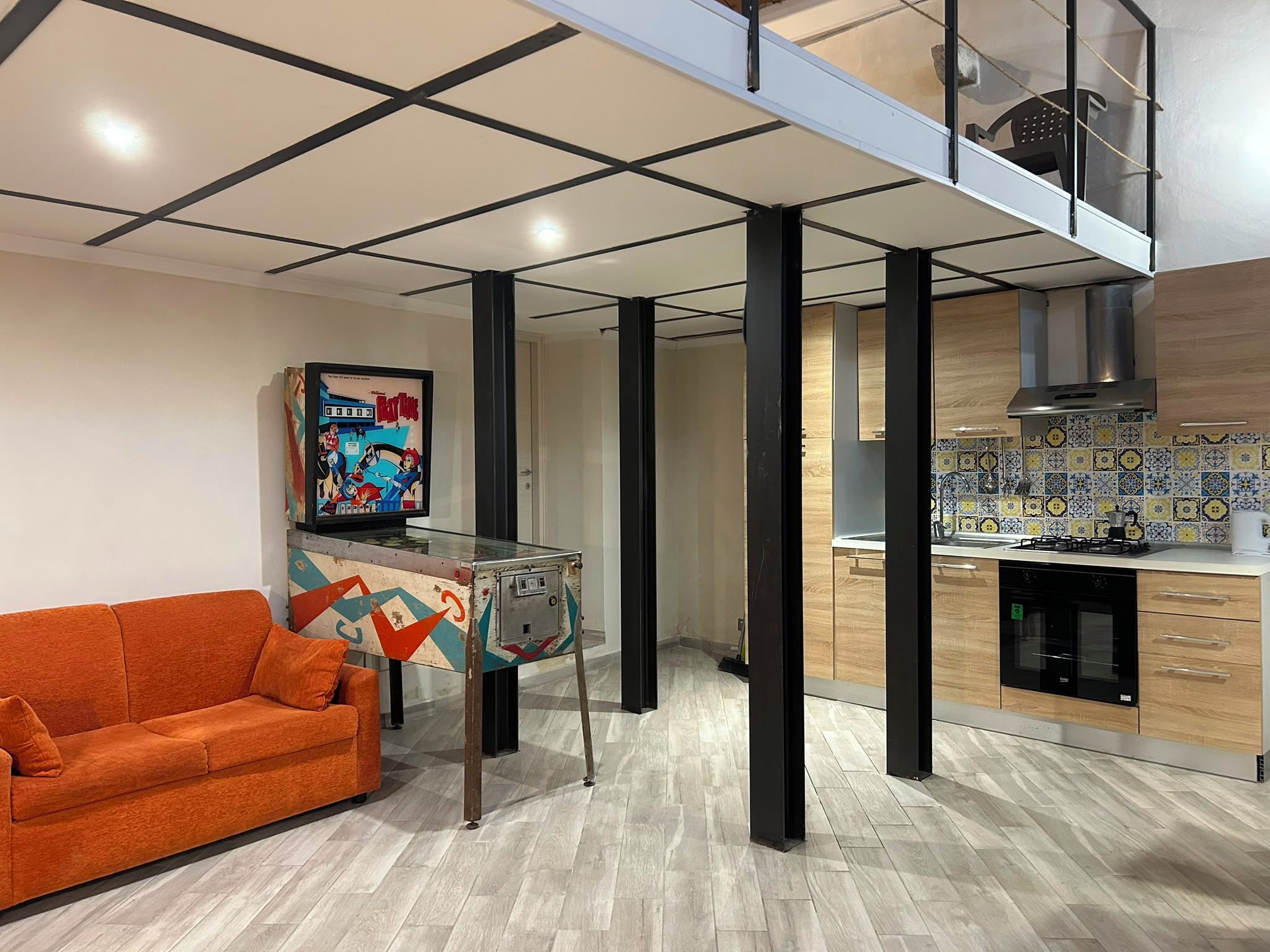 Een moderne woonruimte met een bank, een salontafel met glazen blad en een keuken met fornuis en oven.
