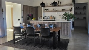 Una cocina moderna con una isla central, sillas negras y una mesa de comedor preparada para cuatro.