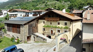 A traditional chalet with a wooden facade, a balcony with flowers, and a stone building adjacent to it.