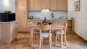 A modern kitchen with wooden cabinets, a dining table with chairs, and a microwave. - Apartment 'Linslhof Terlaner' with Mountain View, Private Terrace and Wi-Fi (Terlano)
