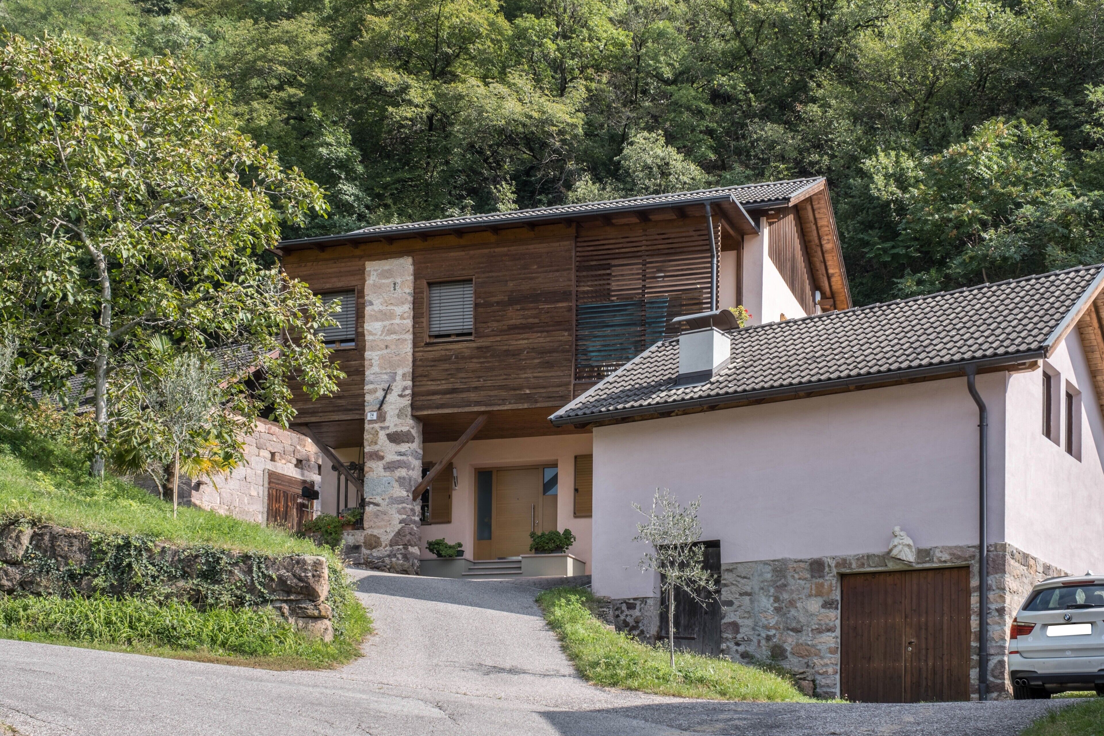 A two-story house with a stone facade, wooden accents, and a tiled roof.
