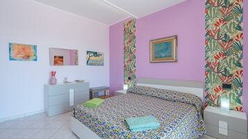 A bedroom with a bed, bedside tables, a dresser, and artwork on the walls.