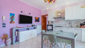 Eine moderne Küche mit Fernseher, einem Esstisch mit Stühlen und einer dekorativen Pendelleuchte.