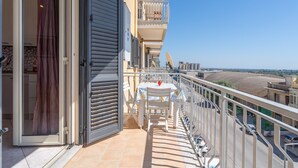 Ein Balkon mit Tisch und Stühlen, einer Schiebetür und Blick auf die Straße.