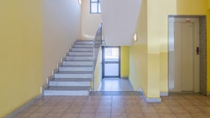 Eine Treppe, die zu einer oberen Etage führt, eine Tür am Fußende und ein Aufzug auf der rechten Seite.