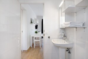 Ein modernes Badezimmer mit weißen Fliesen, einem Waschbecken und einem Spiegel.