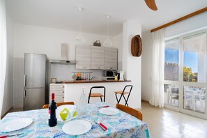 Una cucina moderna con zona pranzo, che include un tavolo per due apparecchiato con piatti, una bottiglia e dei bicchieri.