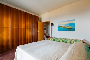 Una camera da letto con un letto, un armadio in legno, un quadro e un comodino.