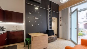 Una cocina moderna con una mesa de madera, una silla verde, un televisor y un reloj en la pared.