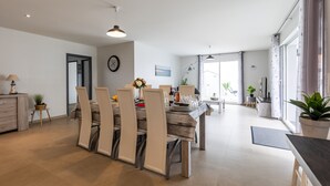A modern dining area with a wooden table and chairs, a clock on the wall, and a view to the living area. - Villa "Bassin d'Arcachon" with Private Pool, Private Terraces and Wi-Fi (ARES)