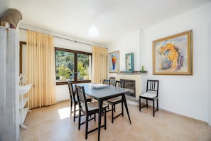 A dining area with a table and chairs, a fireplace, and a large painting on the wall.