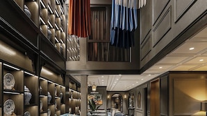 Un vestíbulo amplio con techo alto, una zona de estar con sofás y sillones, y una pared decorativa con estantes llenos de jarrones.
